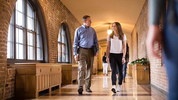 Students walking through the corridor between tower and the library