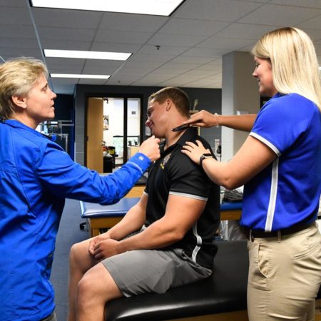 St. Scholastica professor teaching an athletic training technique in a lab setting.
