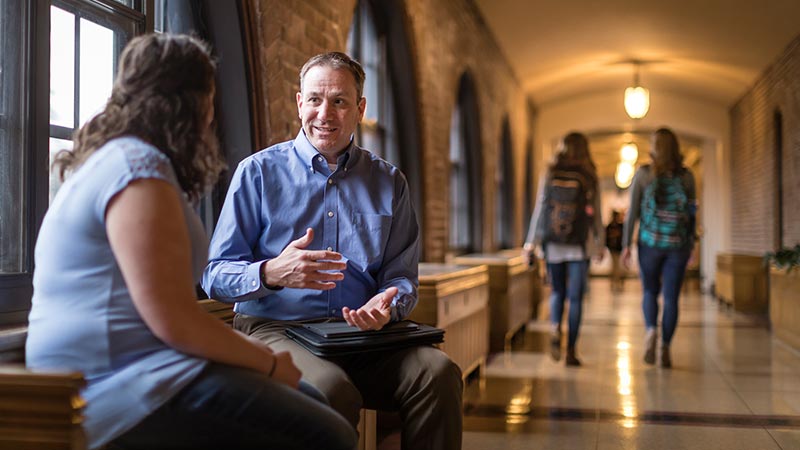 Faculty meeting with a student in the Cloister Walk at St. Scholastica.