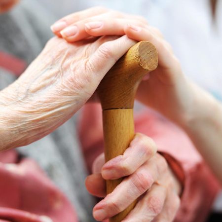A caregiver holding and elderly person's hand.